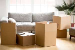 Cardboard carton boxes with personal belongings household stuff in modern living room, many packed containers on moving day in new home, relocation or house removals delivery service concept